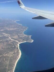 Airplane wing over the ocean approaching Cabo San Lucas.