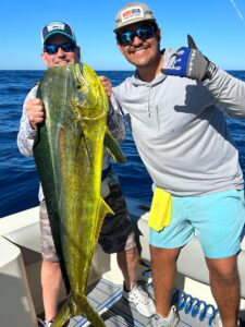 MarVida crew member and a fisherman holding a big Mahi Mahi on a boat in Cabo San Lucas.